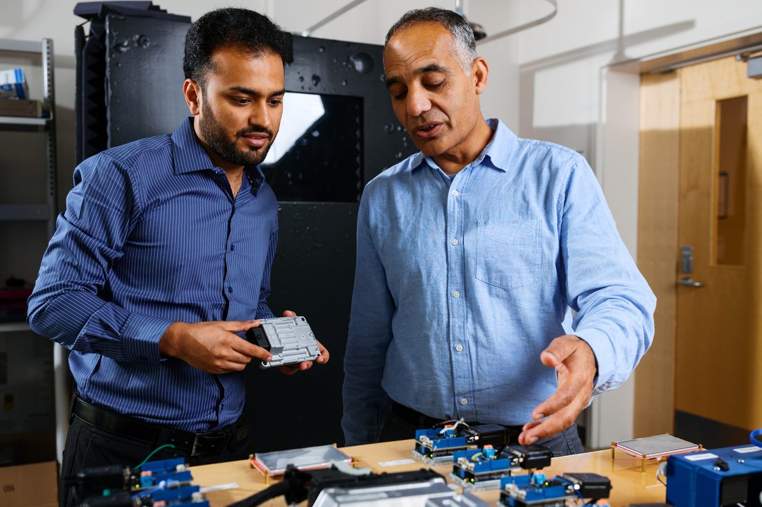 Examining an electronic control unit with Prof. Hafiz Malik, with identical modules laid out on the bench